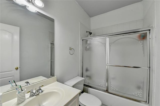 bathroom featuring enclosed tub / shower combo, toilet, and vanity