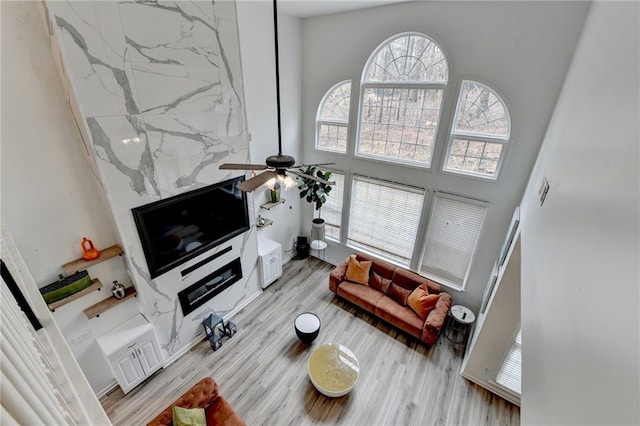 living room featuring ceiling fan, a towering ceiling, and light wood finished floors