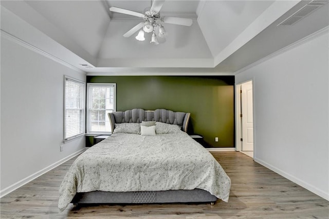 bedroom featuring visible vents, baseboards, wood finished floors, and ornamental molding