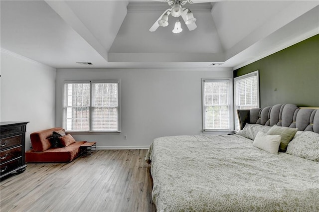 bedroom with visible vents, light wood-style flooring, baseboards, and a tray ceiling