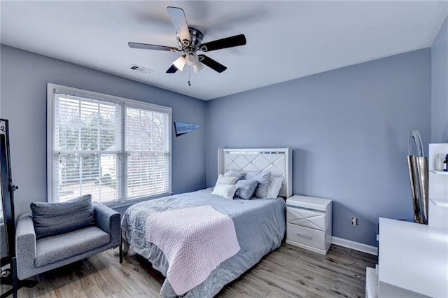 bedroom featuring light wood-type flooring, visible vents, baseboards, and a ceiling fan