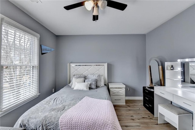 bedroom featuring baseboards, light wood finished floors, and ceiling fan