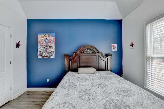 bedroom with vaulted ceiling, baseboards, and wood finished floors