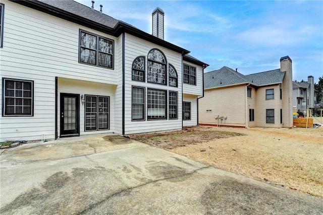 rear view of property featuring a chimney and a patio