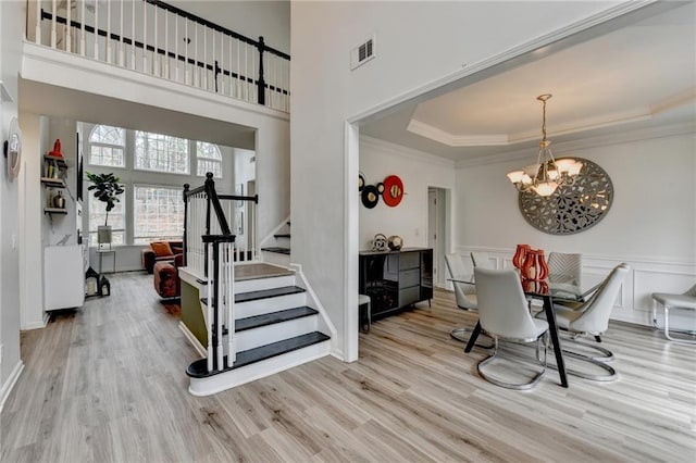 dining room featuring visible vents, ornamental molding, a tray ceiling, wood finished floors, and stairway