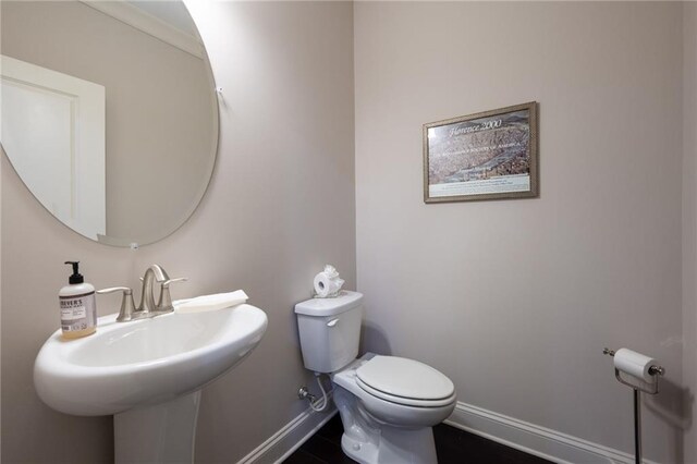 bathroom with toilet, sink, and tile patterned flooring