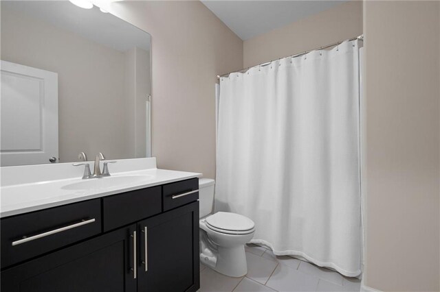 bathroom with toilet, vanity, and tile patterned flooring