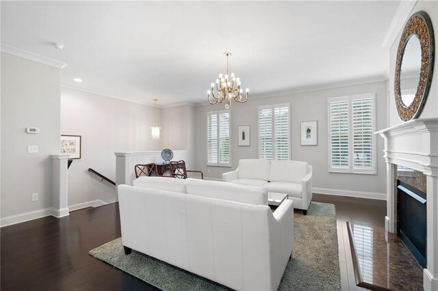 living room featuring a premium fireplace, dark hardwood / wood-style floors, crown molding, and an inviting chandelier