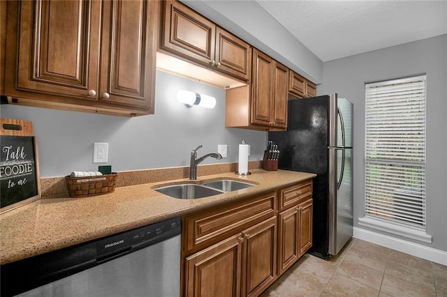 kitchen featuring a textured ceiling, sink, light tile patterned floors, and stainless steel appliances