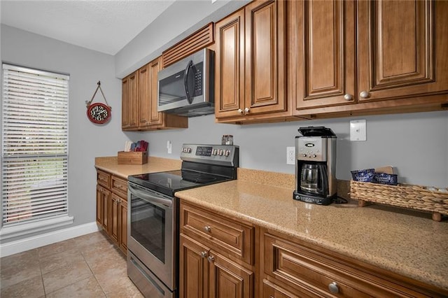 kitchen featuring light stone countertops, light tile patterned flooring, and stainless steel appliances