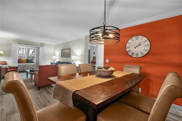 dining area with light hardwood / wood-style floors, ornamental molding, and a notable chandelier