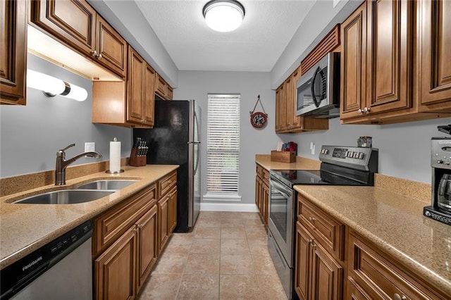 kitchen with light stone countertops, light tile patterned floors, stainless steel appliances, and sink