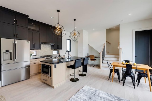 kitchen featuring high quality fridge, a sink, a breakfast bar, light wood-style floors, and decorative backsplash