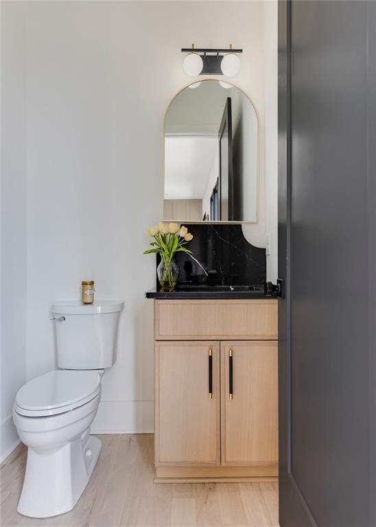 half bathroom with toilet, vanity, and baseboards