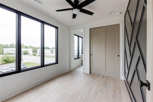 unfurnished bedroom featuring multiple windows, light wood-style floors, a closet, and baseboards