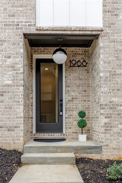 view of exterior entry featuring brick siding