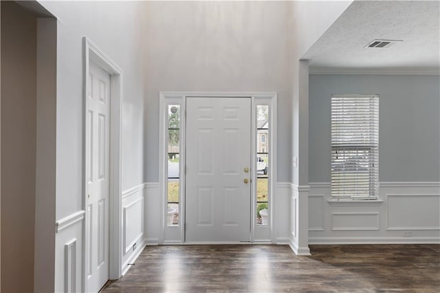 entrance foyer featuring dark hardwood / wood-style floors, a textured ceiling, and crown molding