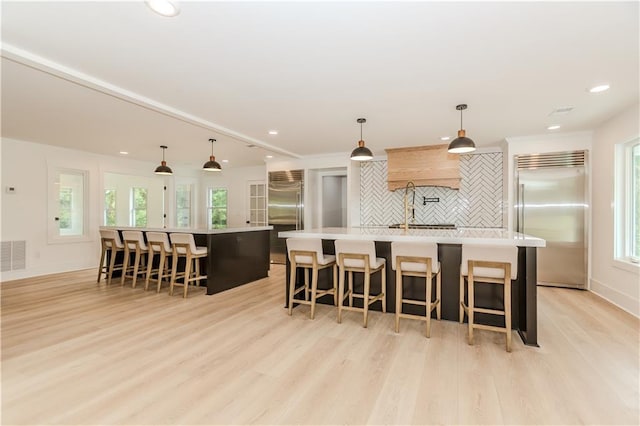 kitchen with tasteful backsplash, a large island, pendant lighting, and stainless steel built in refrigerator