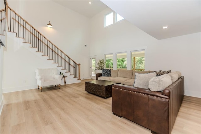 living room featuring a towering ceiling and light hardwood / wood-style floors