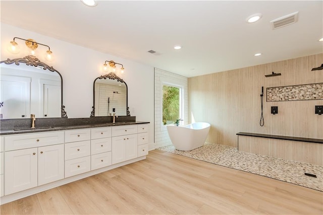 bathroom with plus walk in shower, hardwood / wood-style floors, and vanity