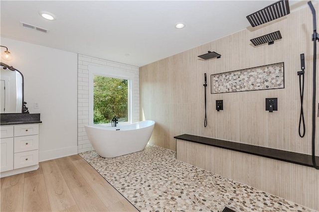 bathroom with hardwood / wood-style flooring, vanity, and shower with separate bathtub