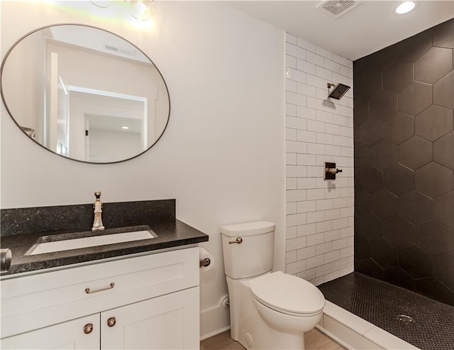 bathroom with tiled shower, vanity, and toilet