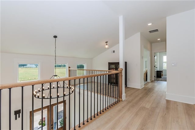 hall with lofted ceiling, light hardwood / wood-style flooring, and a notable chandelier