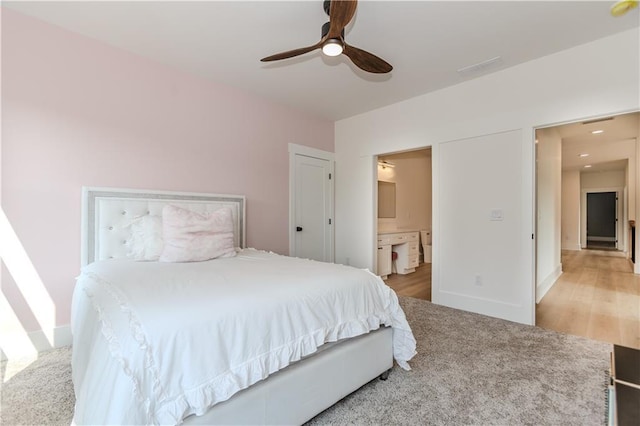 bedroom featuring ceiling fan, light colored carpet, and ensuite bath