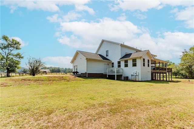 rear view of property with a yard, a deck, and central AC unit