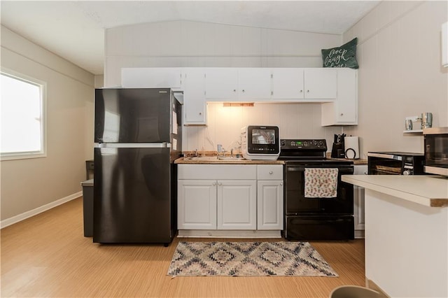 kitchen featuring white cabinetry, sink, black range with electric cooktop, stainless steel fridge, and lofted ceiling