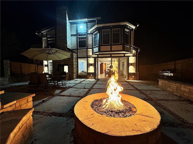 back house at twilight featuring an outdoor fire pit and a patio