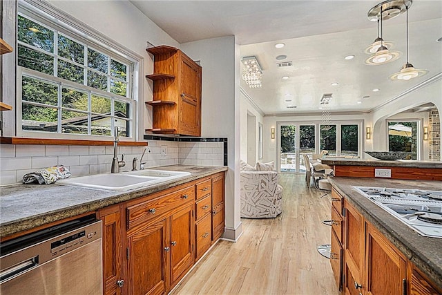 kitchen featuring backsplash, dishwasher, sink, hanging light fixtures, and light wood-type flooring