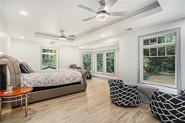 bedroom featuring ceiling fan, a tray ceiling, light hardwood / wood-style flooring, and crown molding