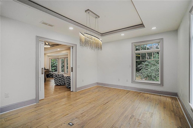 unfurnished room with light hardwood / wood-style floors, a wealth of natural light, a tray ceiling, and ceiling fan