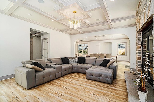 living room with beamed ceiling, an inviting chandelier, light hardwood / wood-style floors, ornamental molding, and coffered ceiling