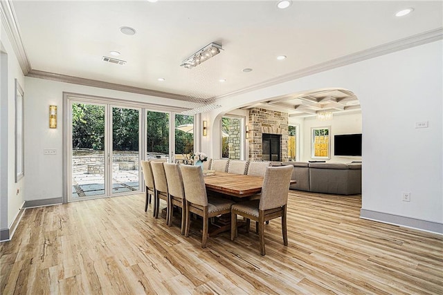 dining space featuring coffered ceiling, a fireplace, crown molding, light hardwood / wood-style flooring, and beamed ceiling