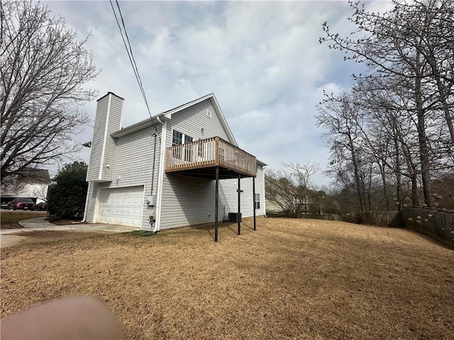 rear view of property featuring a garage, a chimney, central AC, and a yard