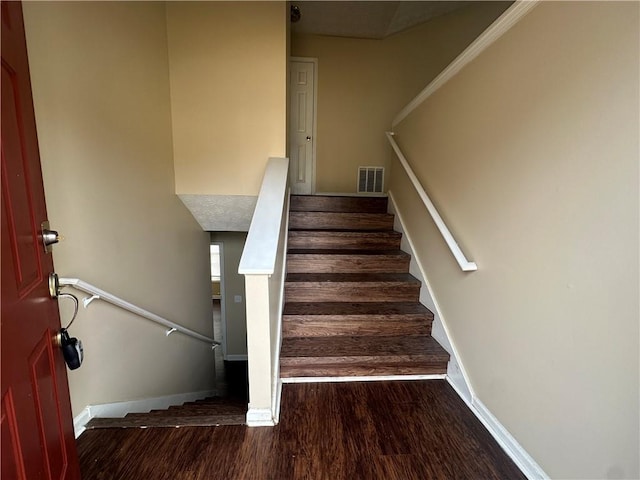 staircase with wood finished floors, visible vents, and baseboards