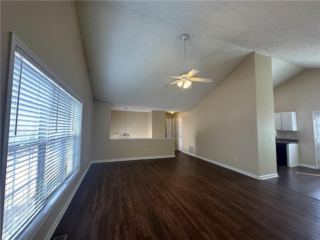 unfurnished living room with dark wood-type flooring, lofted ceiling, ceiling fan, and baseboards