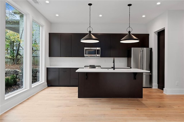 kitchen with pendant lighting, an island with sink, a wealth of natural light, and appliances with stainless steel finishes