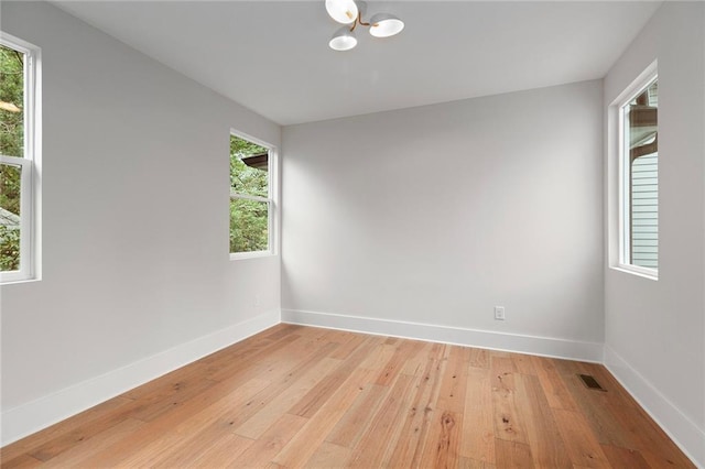 spare room with light wood-type flooring and an inviting chandelier