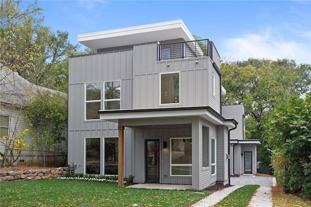 back of property featuring a balcony and a lawn