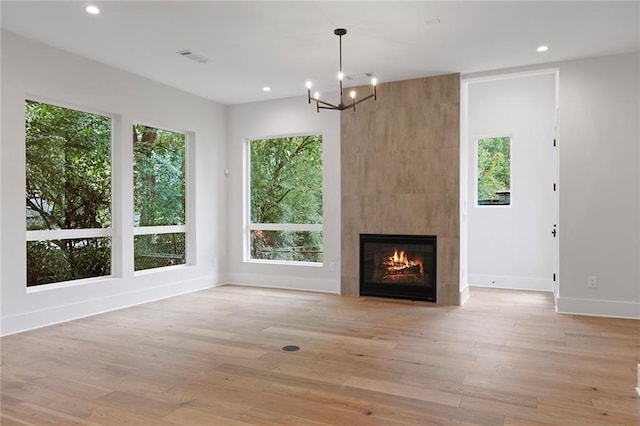 unfurnished living room featuring a fireplace, an inviting chandelier, and light hardwood / wood-style flooring