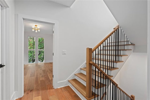 stairway featuring hardwood / wood-style flooring and a chandelier