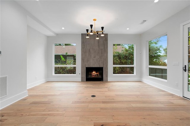 unfurnished living room featuring a large fireplace, light wood-type flooring, and a wealth of natural light