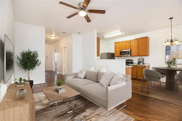 living room with dark wood-type flooring and ceiling fan with notable chandelier