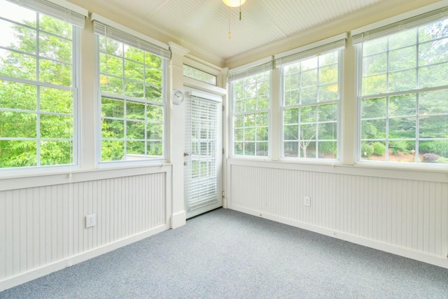 unfurnished sunroom with carpet and ceiling fan