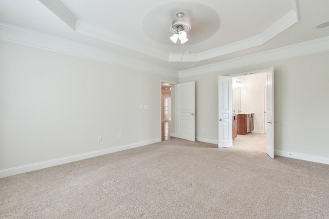unfurnished room featuring a raised ceiling, crown molding, ceiling fan, light carpet, and baseboards