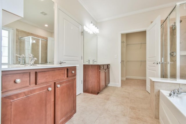 bathroom with a stall shower, crown molding, two vanities, a walk in closet, and tile patterned flooring