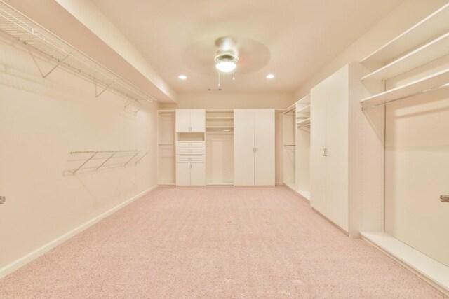 spacious closet with ceiling fan and light colored carpet